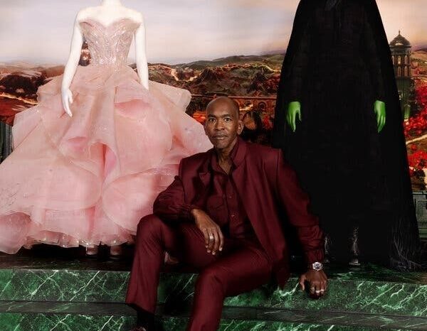 Mann im burgunderroten Anzug zwischen rosa Kleid und schwarzem Hexenkostüm