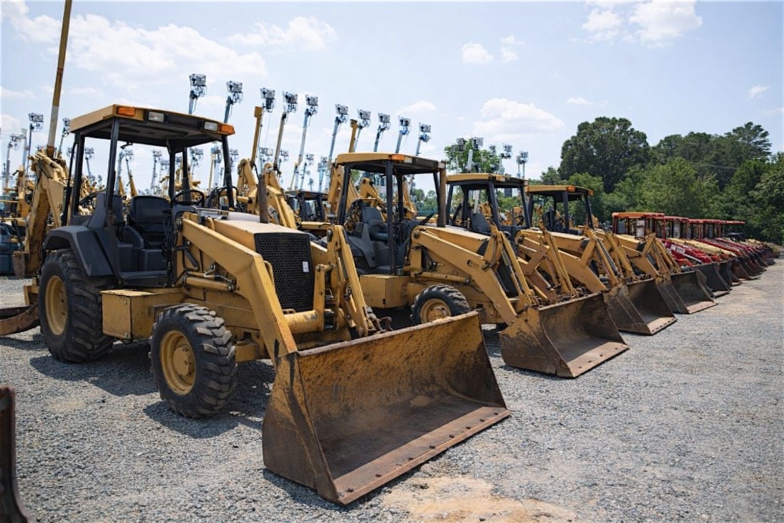 Reihe von gelben Baggern auf einem Auktionsgelände für Baumaschinen.